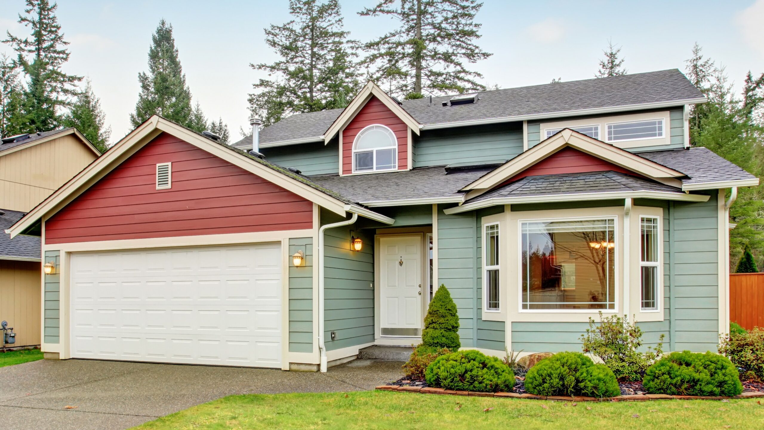 Home with multi-colored red and blue siding with large garage door