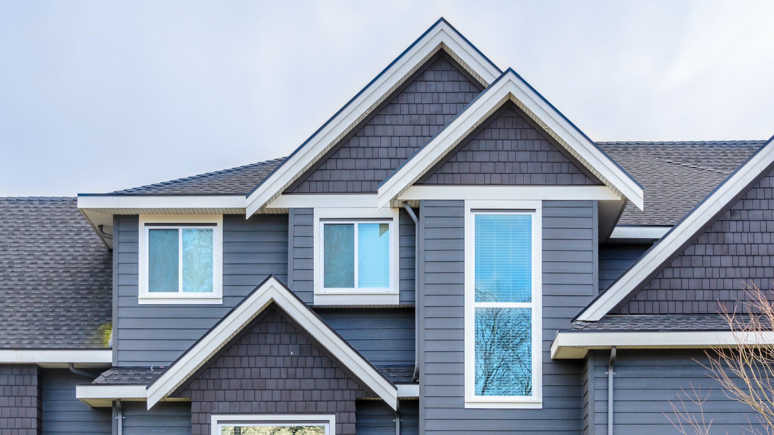 Top of house with blue traditional lap vinyl siding and shingle lap