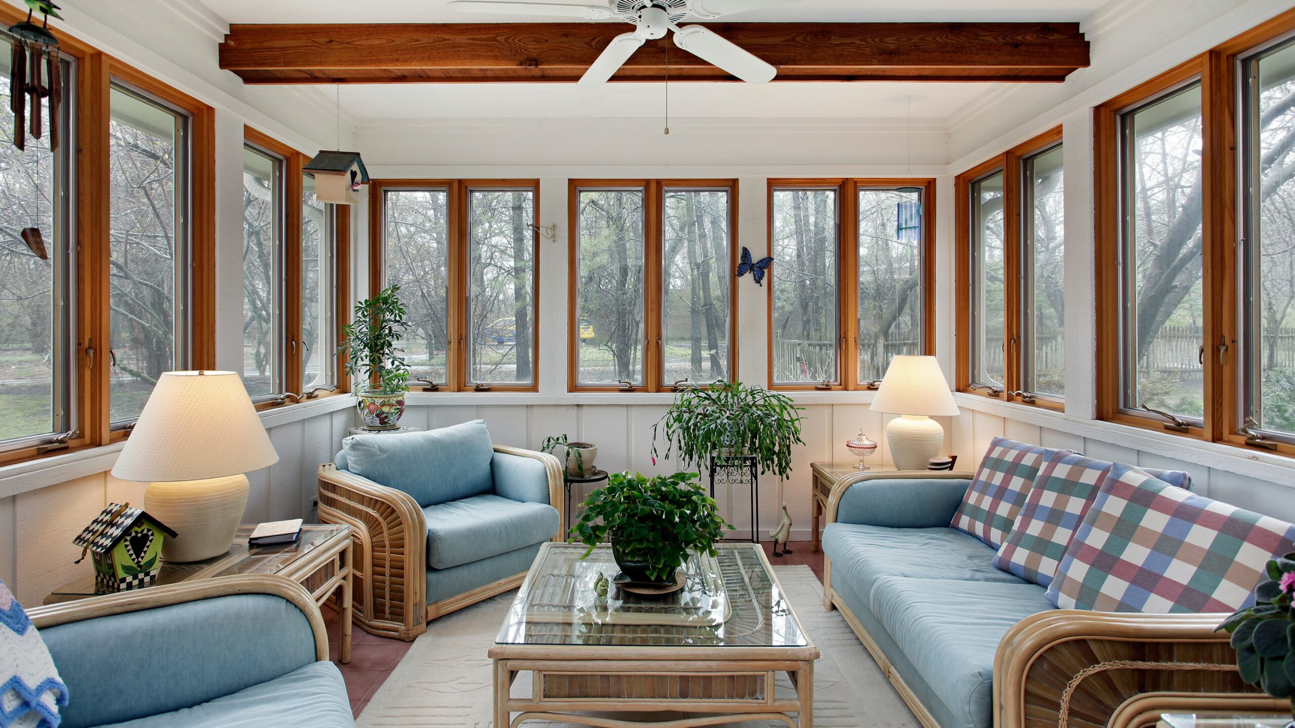 Home sunroom with blue furniture, white walls, and wooden window frames