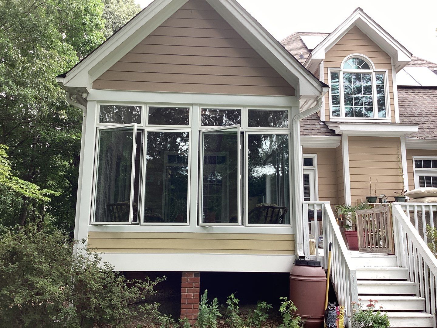 Exterior of a pink home with a sunroom and windows open