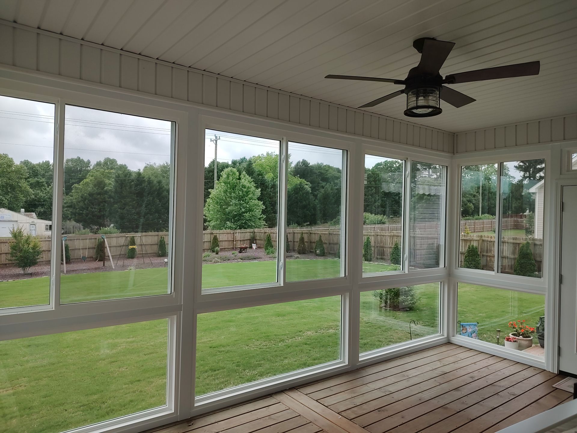 Interior of a sunroom with wood floors looking out at a backyard