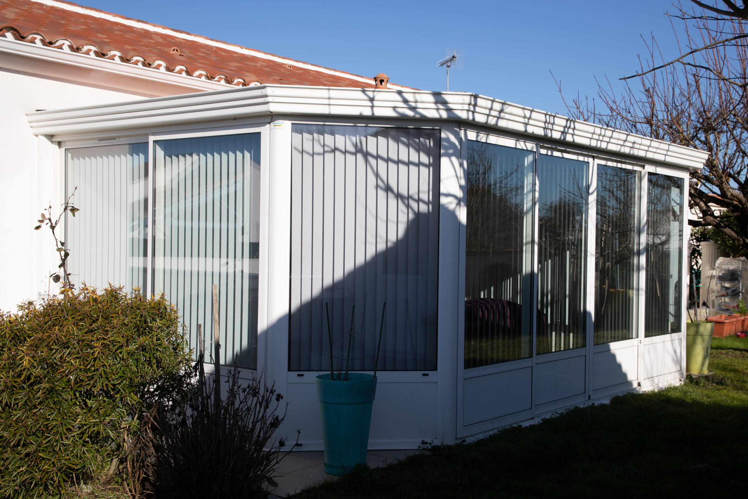 Exterior of a white patio enclosure with windows and white vertical blinds
